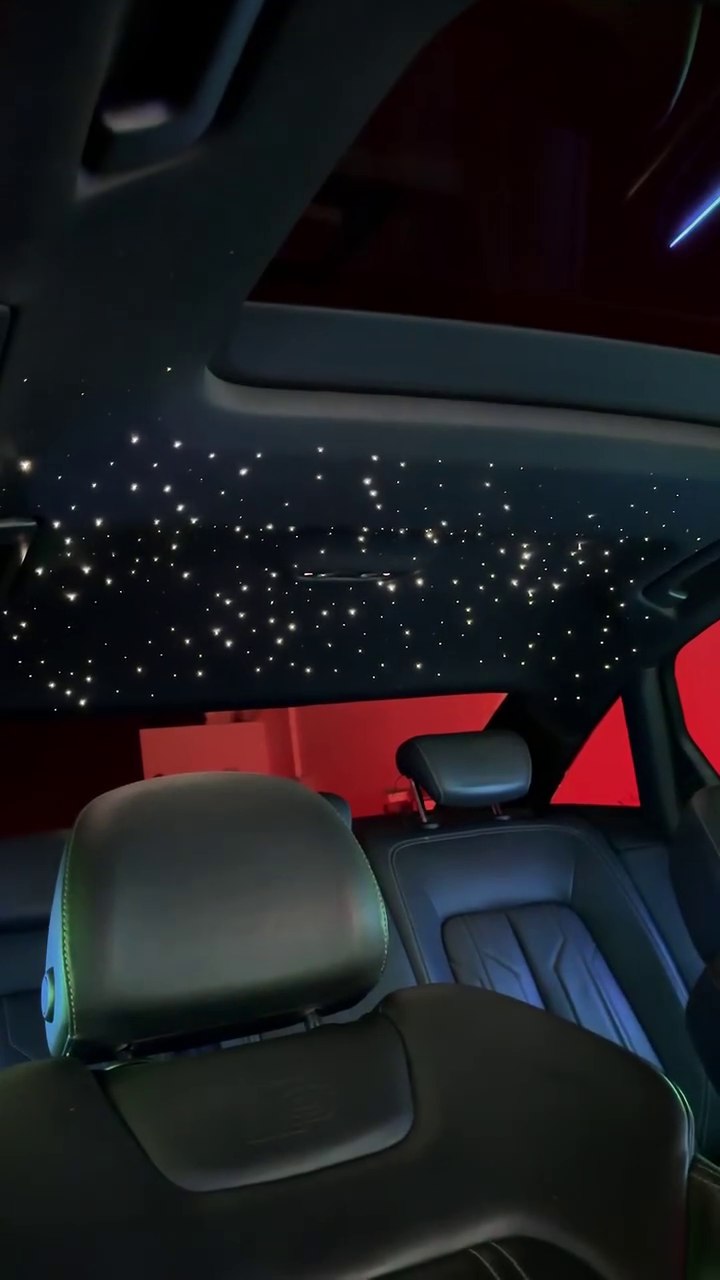White starlights illuminating a vehicle headliner above the rear seats